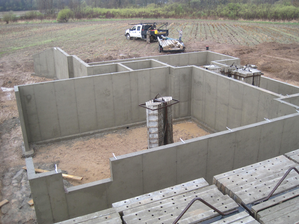 Crews pouring concrete for walls in a field
